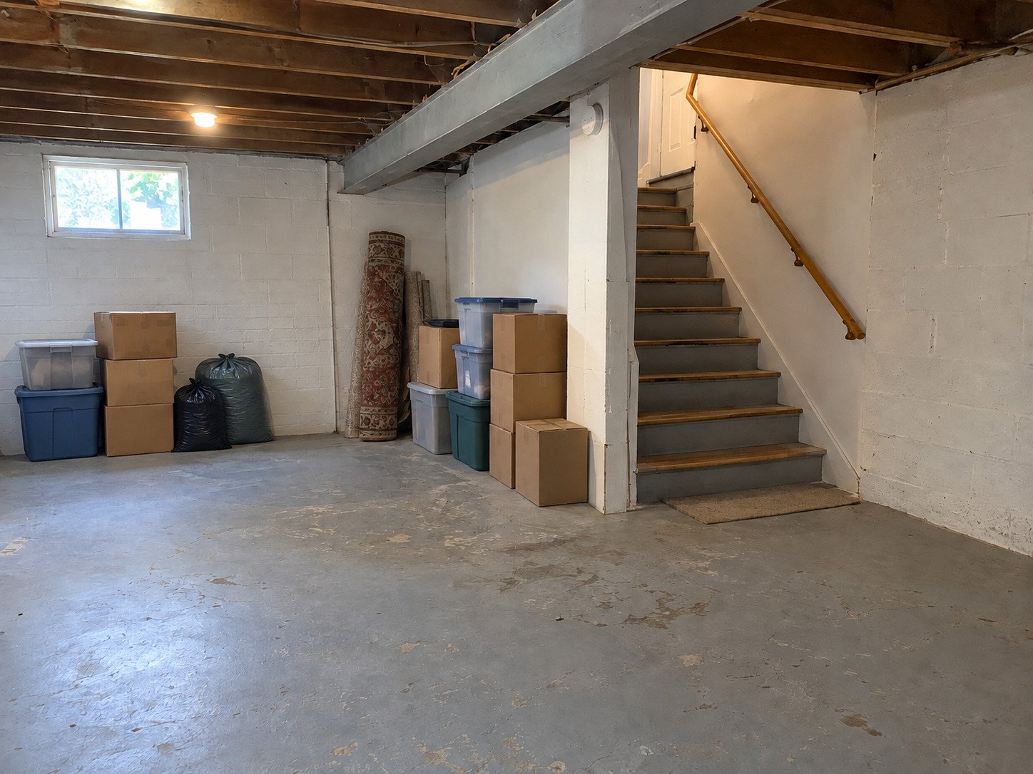 Boxes and bags near a basement stairwell before cleanout.
