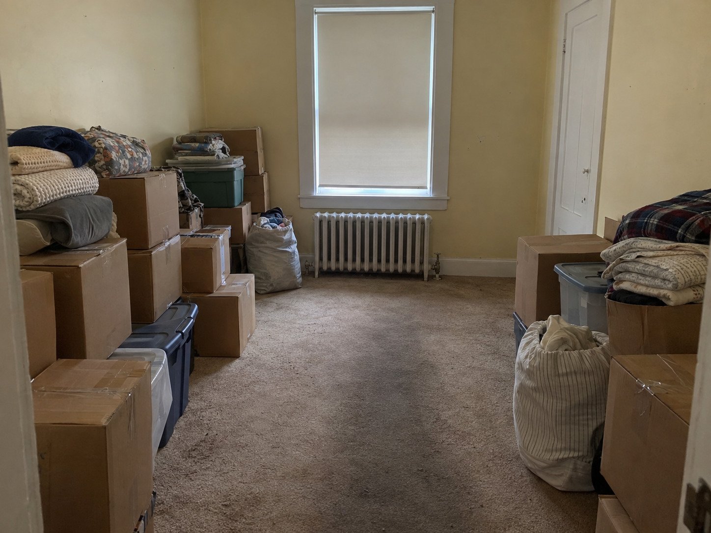Boxes, totes and bags of belongings in a worn room before a hoarding cleanout.