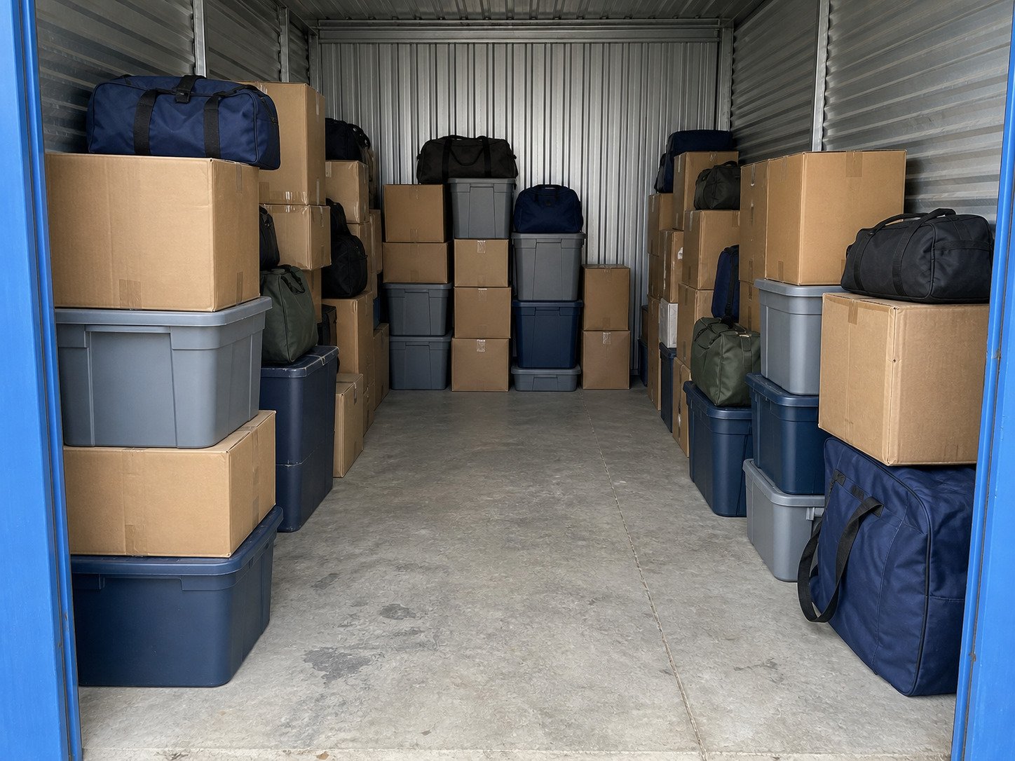 Boxes, plastic totes and duffel bags stored in a metal unit before a cleanout.