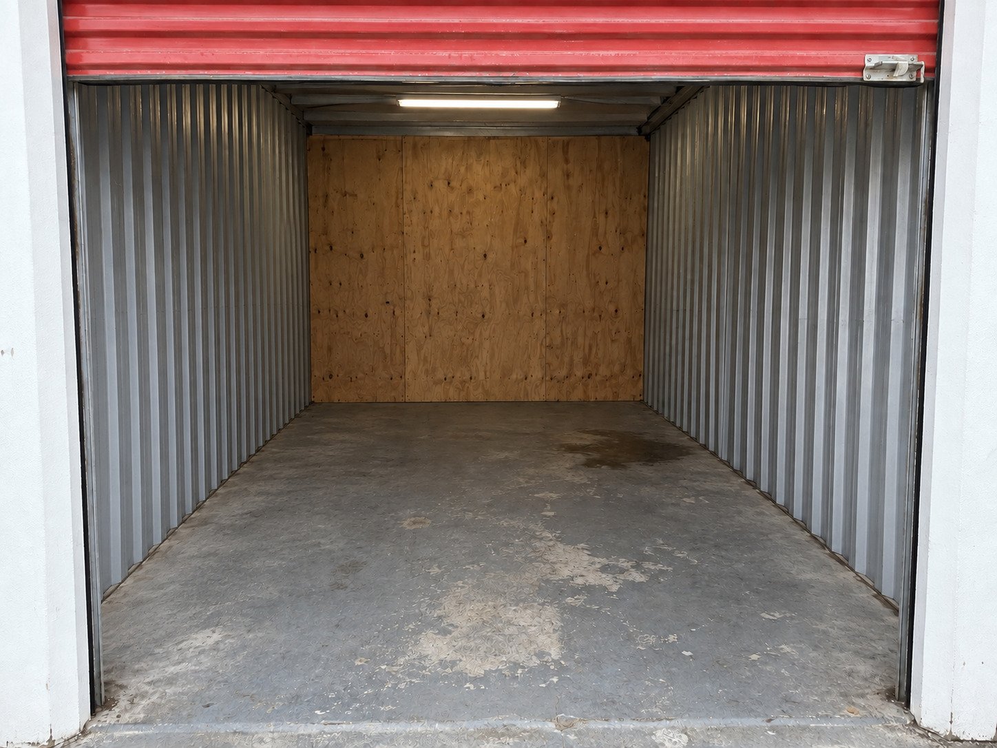 Empty storage locker after a cleanout, retaining the original worn gray floor.