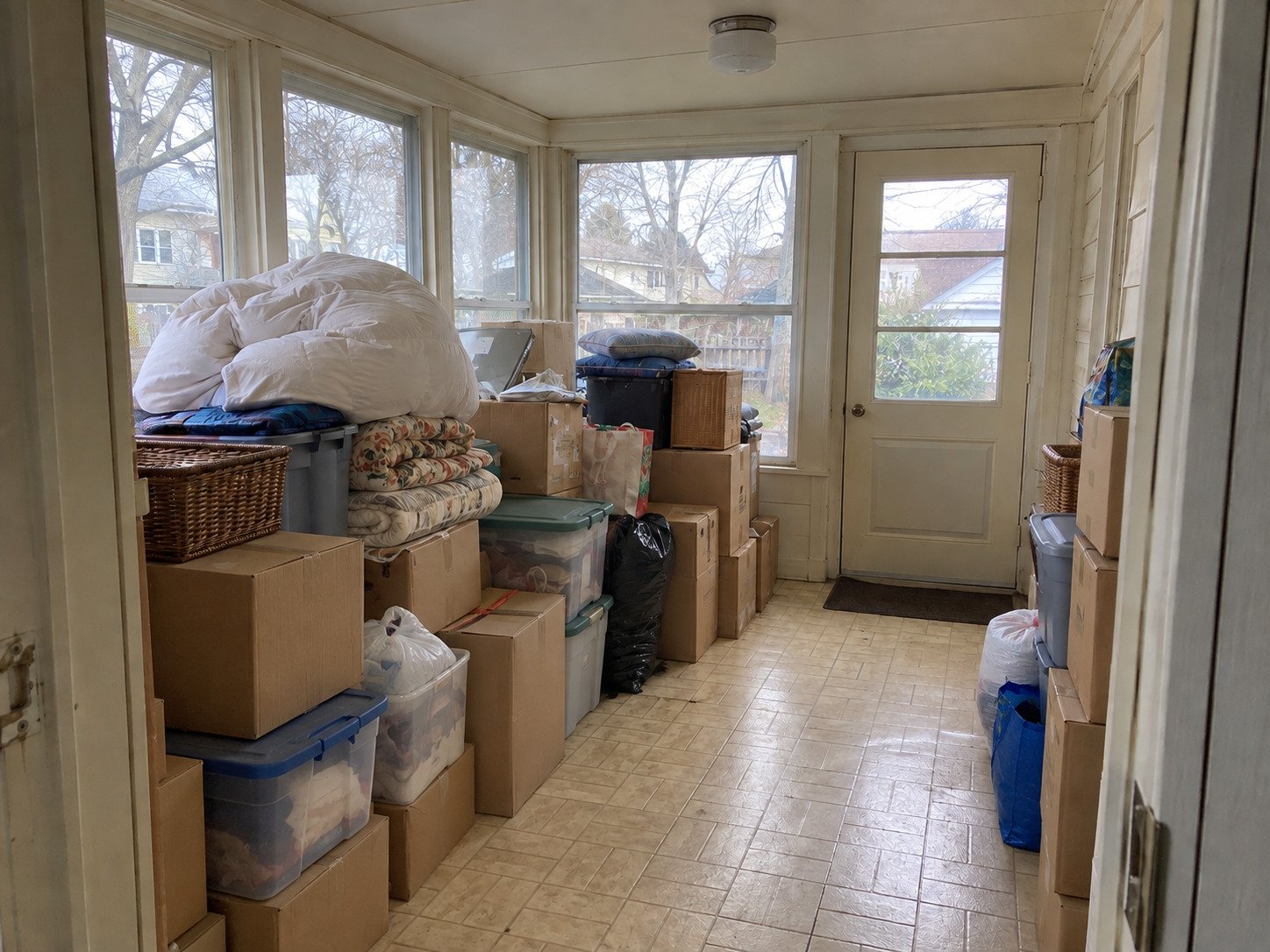 Boxes, totes and bagged belongings filling a sunporch before a hoarding cleanout.