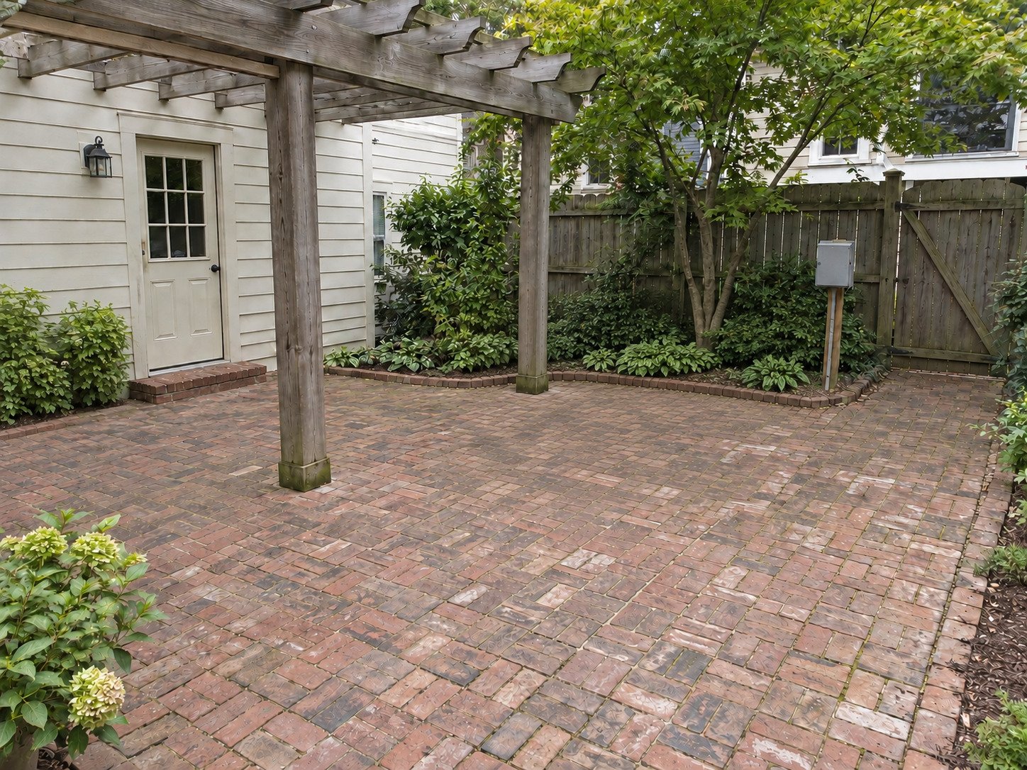 Clear brick courtyard beneath a pergola after hot tub removal.