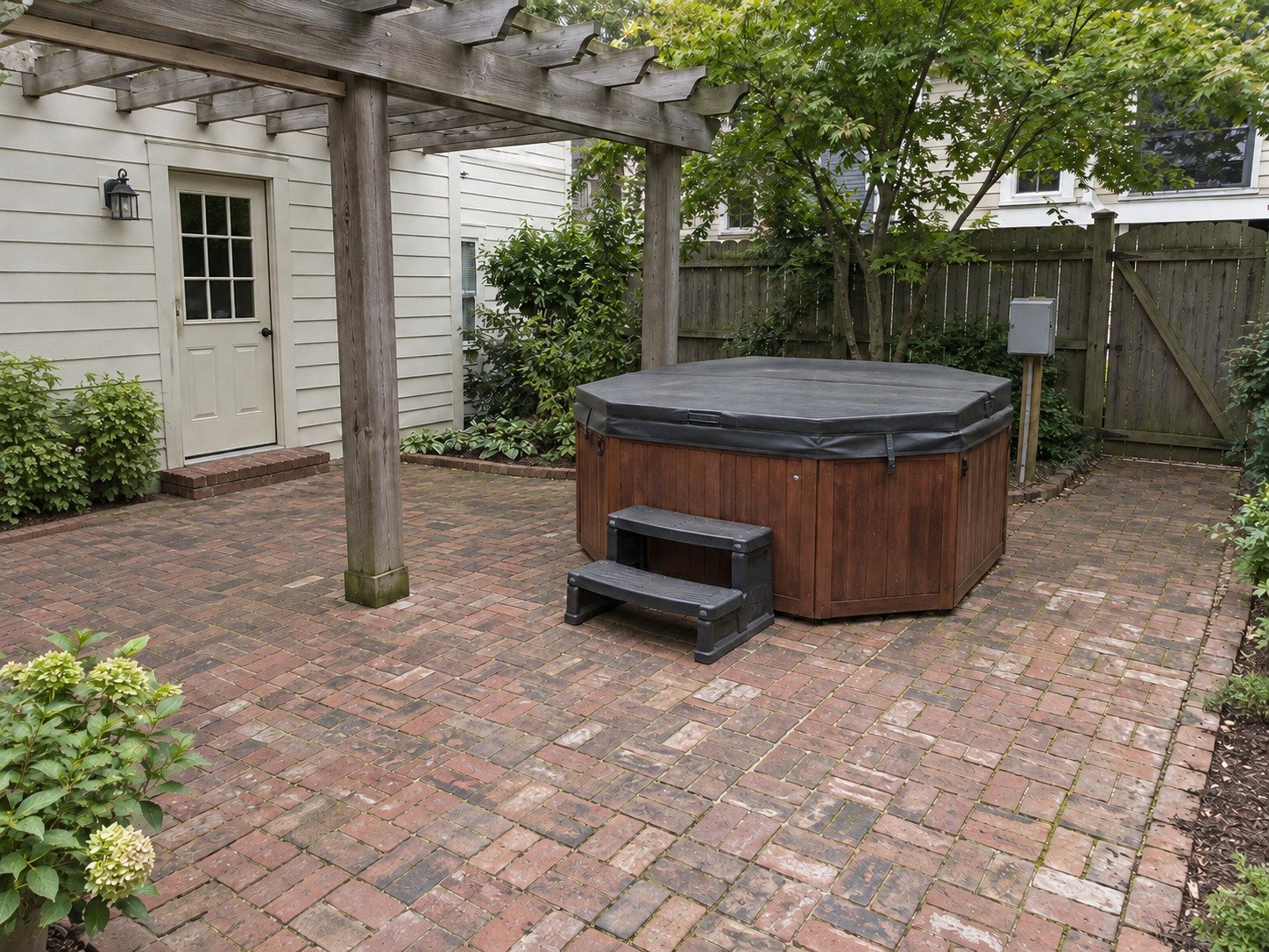 Covered hot tub beneath a pergola before removal, without patio furniture.