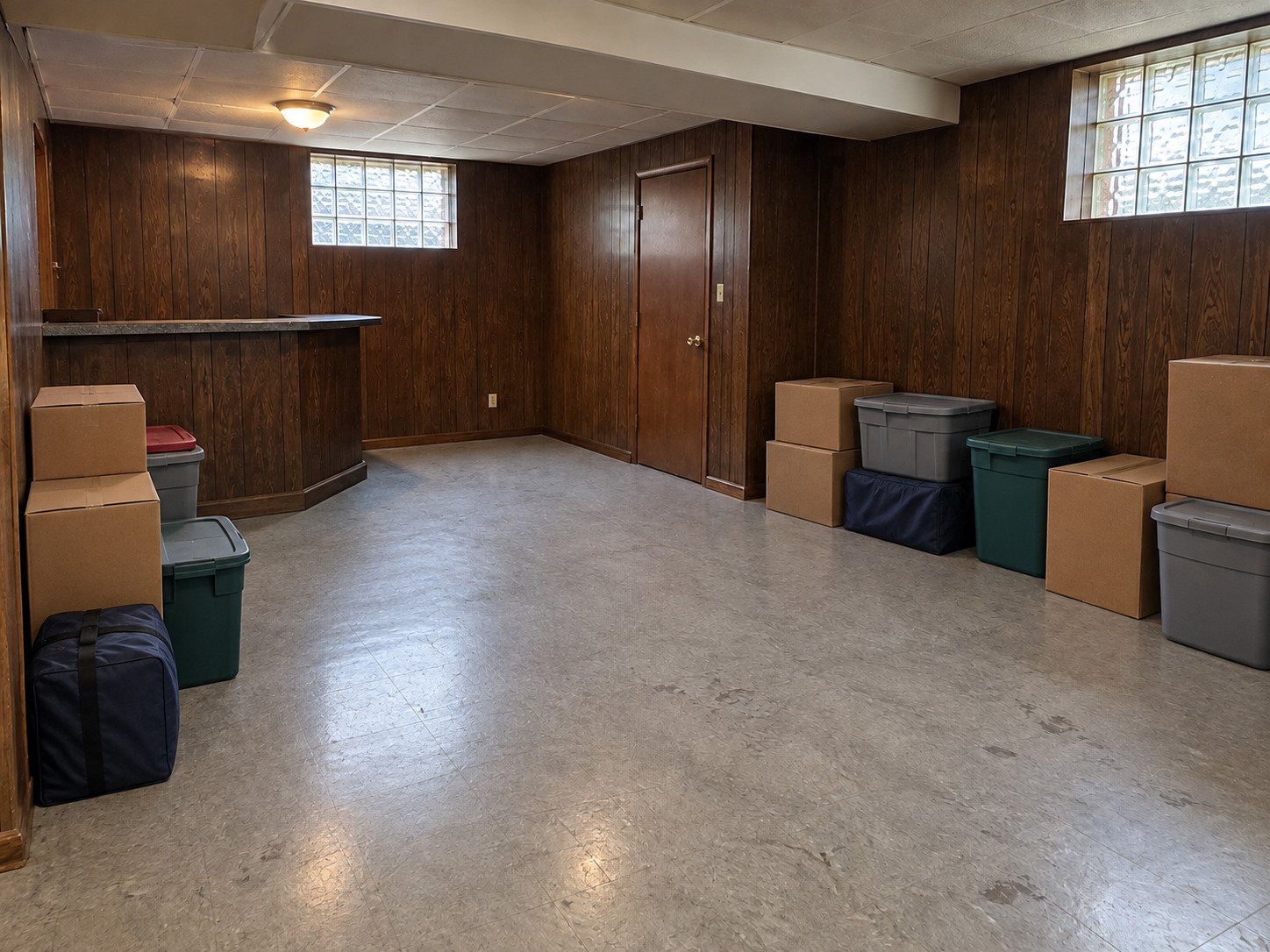 Boxes and totes in a paneled basement before contents cleanout.
