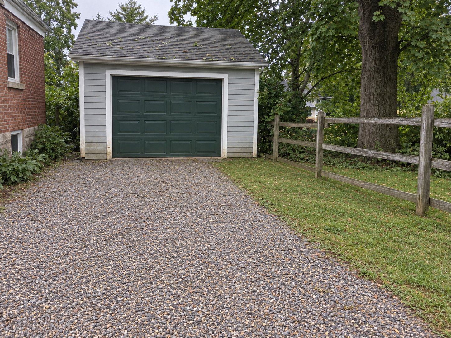 Gravel garage approach clear after storm branches have been removed.