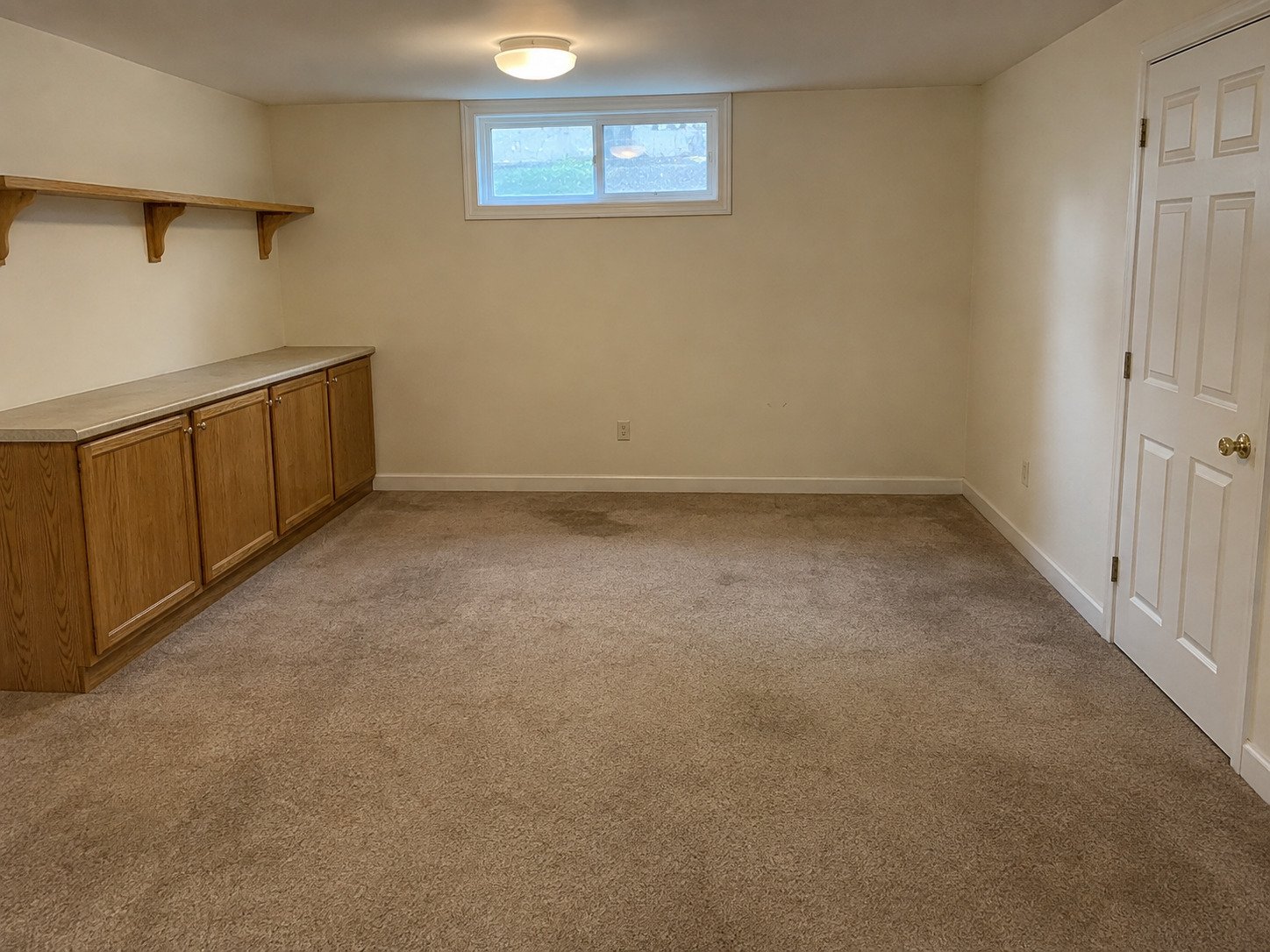 Basement before removal of fixed oak cabinets and a wall shelf.
