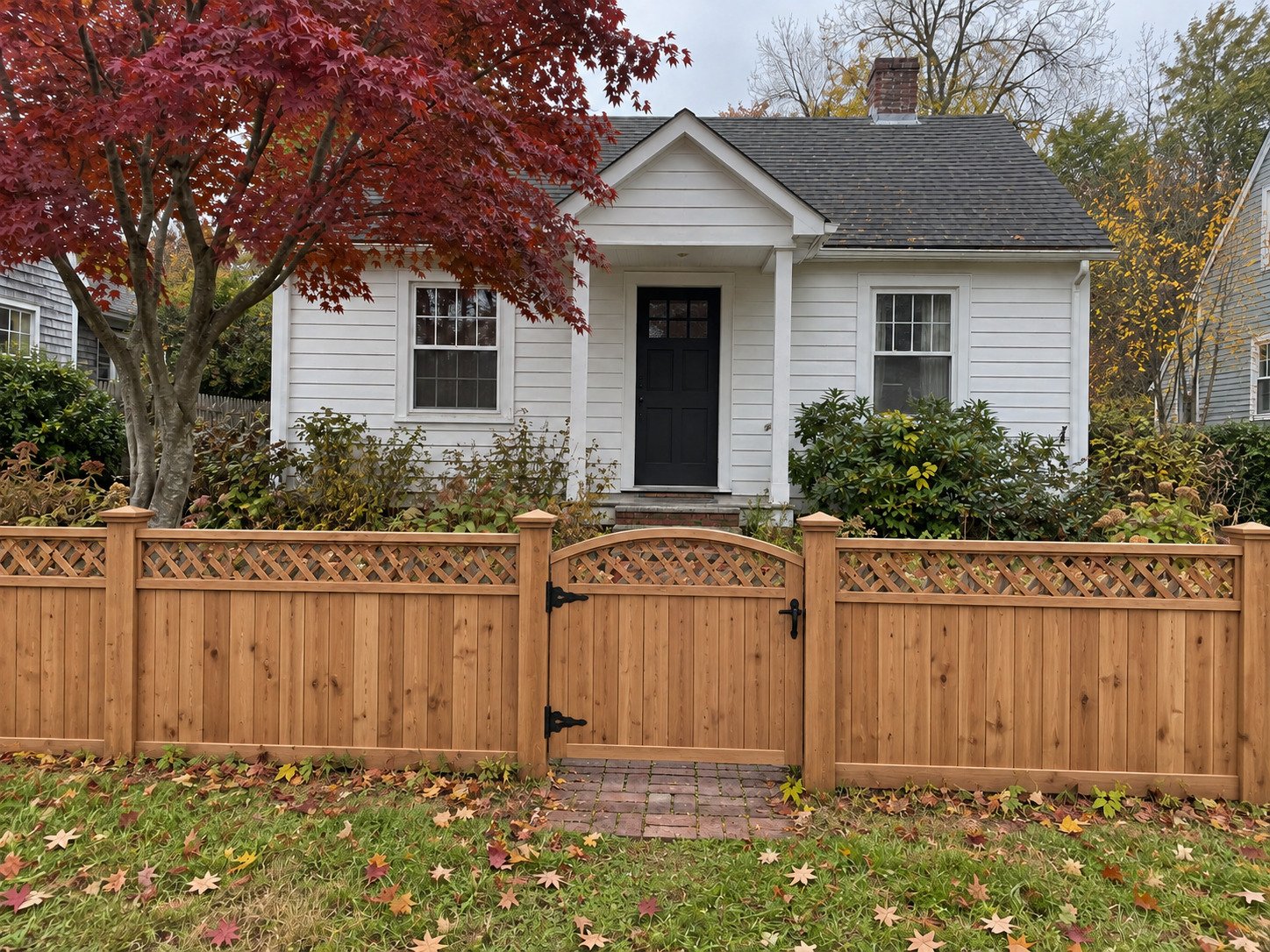 Custom cedar lattice-top fence and arched gate at the same cottage entrance.