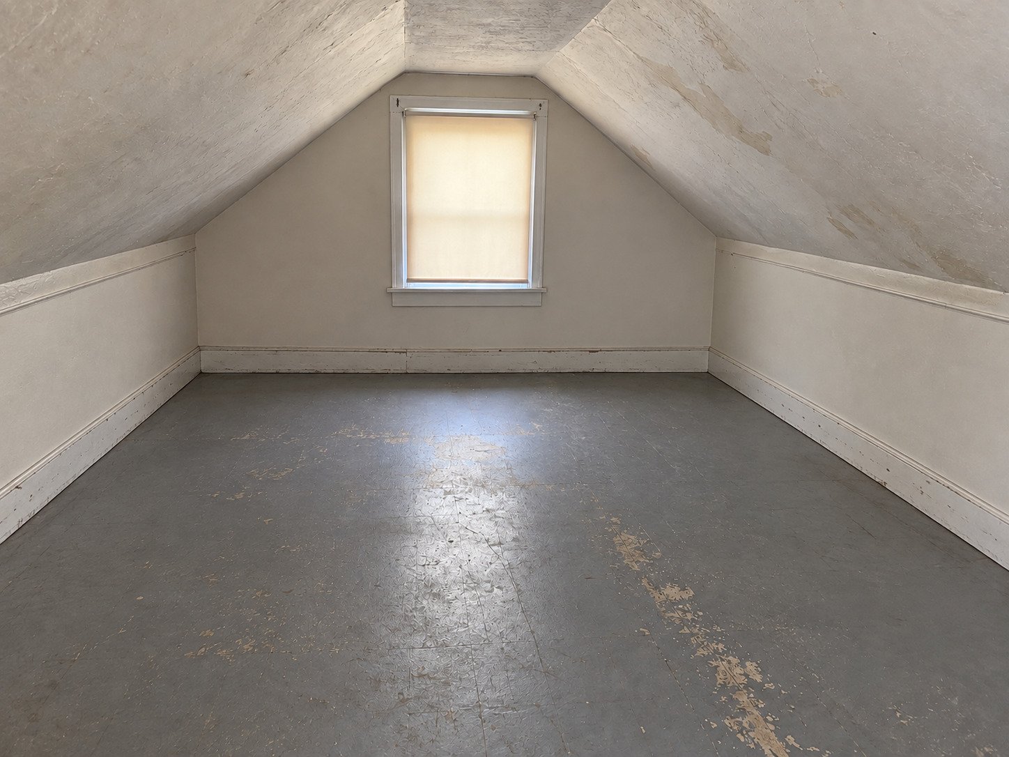 The same attic emptied and swept, with its aged plaster and worn painted floor retained.