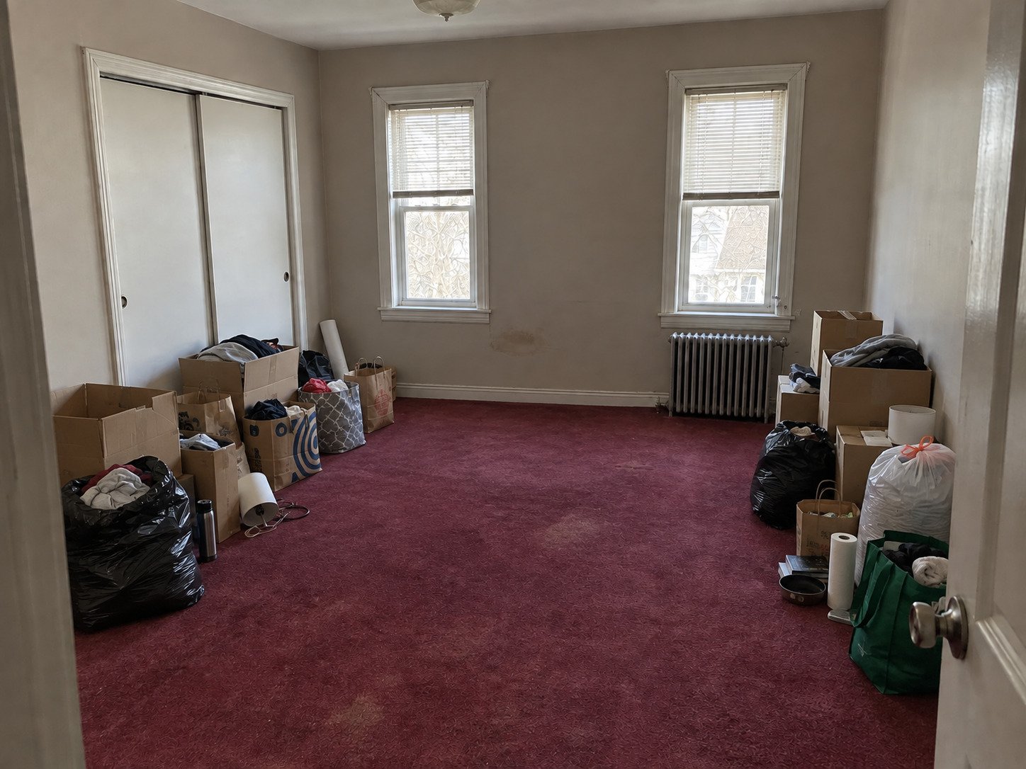 Rental bedroom with boxes and bagged clothing before a turnover cleanout.