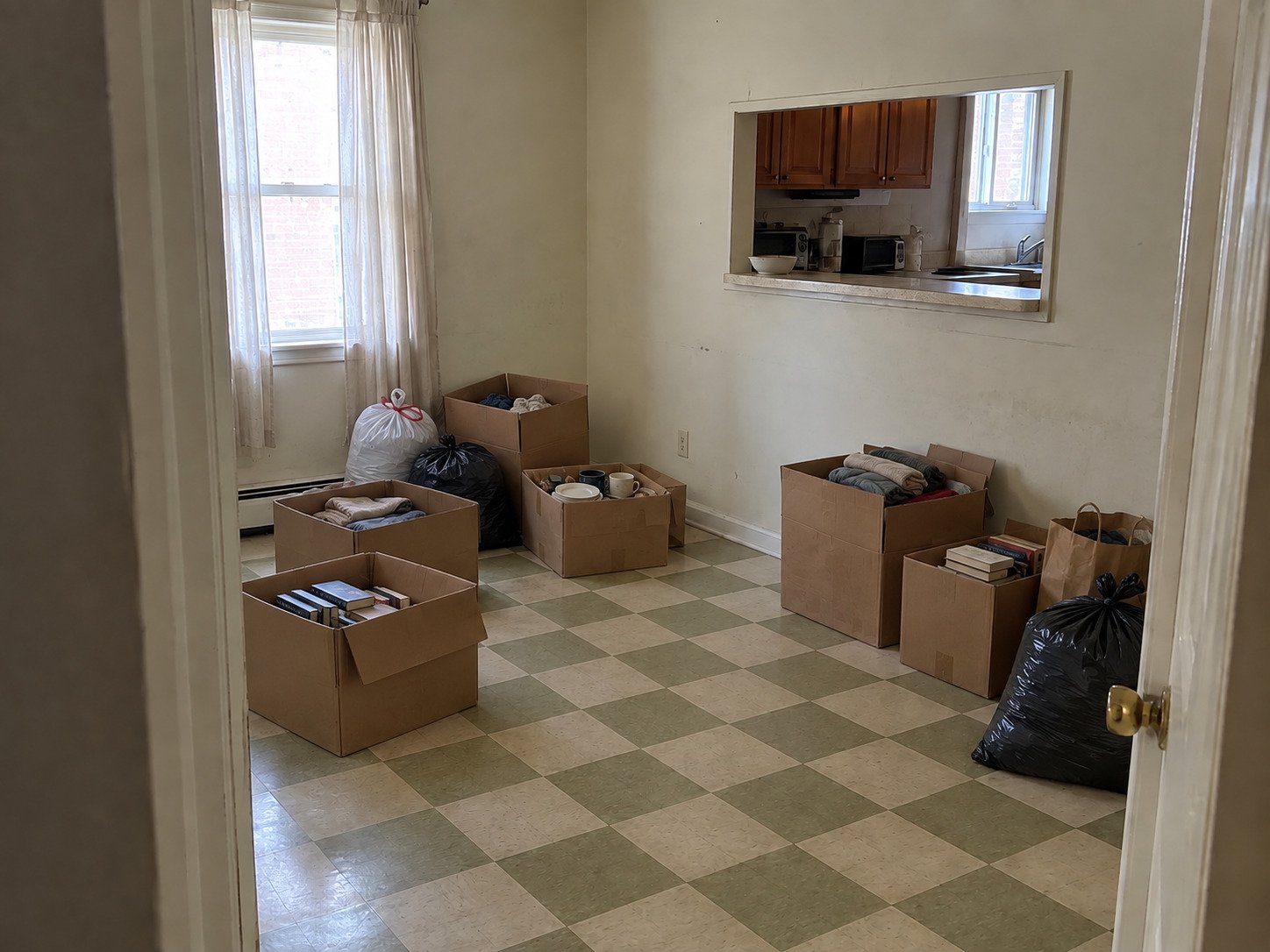 Rental dining nook with boxes and bagged belongings before a turnover cleanout.