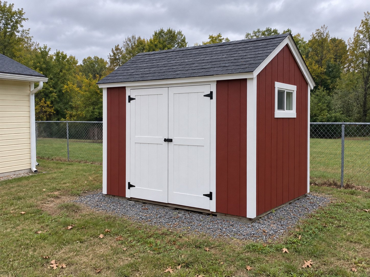 New barn-red garden shed with white double doors on the same property.