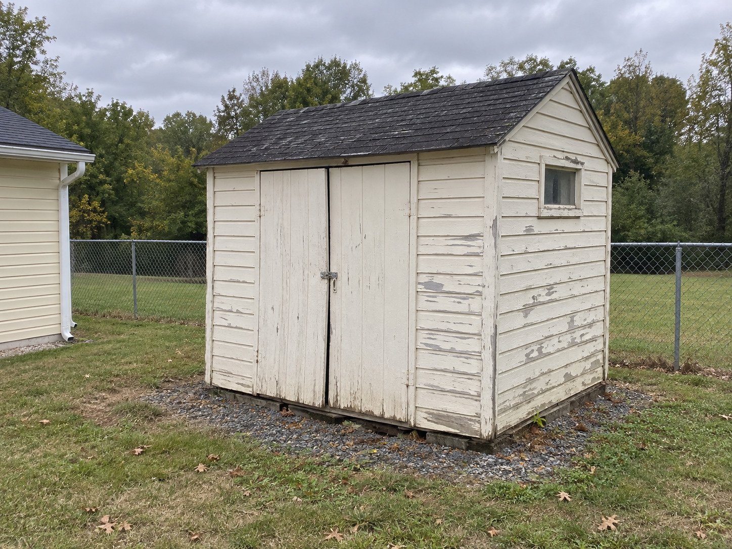 Weathered white garden shed before replacement.