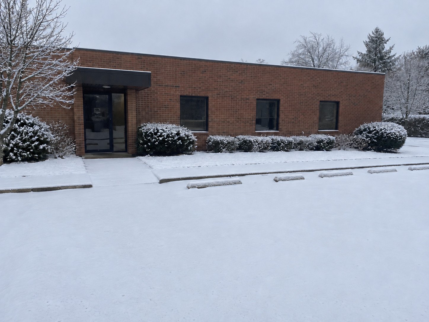 Snow-covered office parking lot and entrance before clearing.