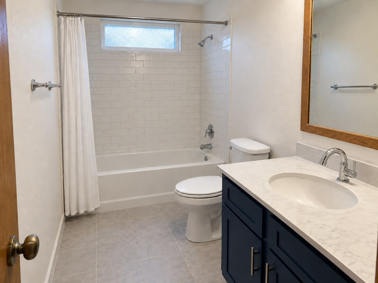 The same representative bathroom refreshed with white tile, a blue vanity and a conventional chrome faucet in the original layout.
