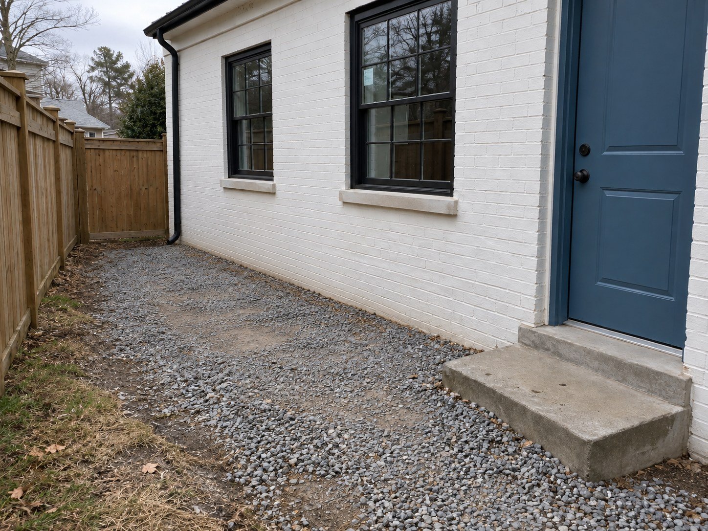 The same gravel side yard cleared of construction debris without resurfacing.