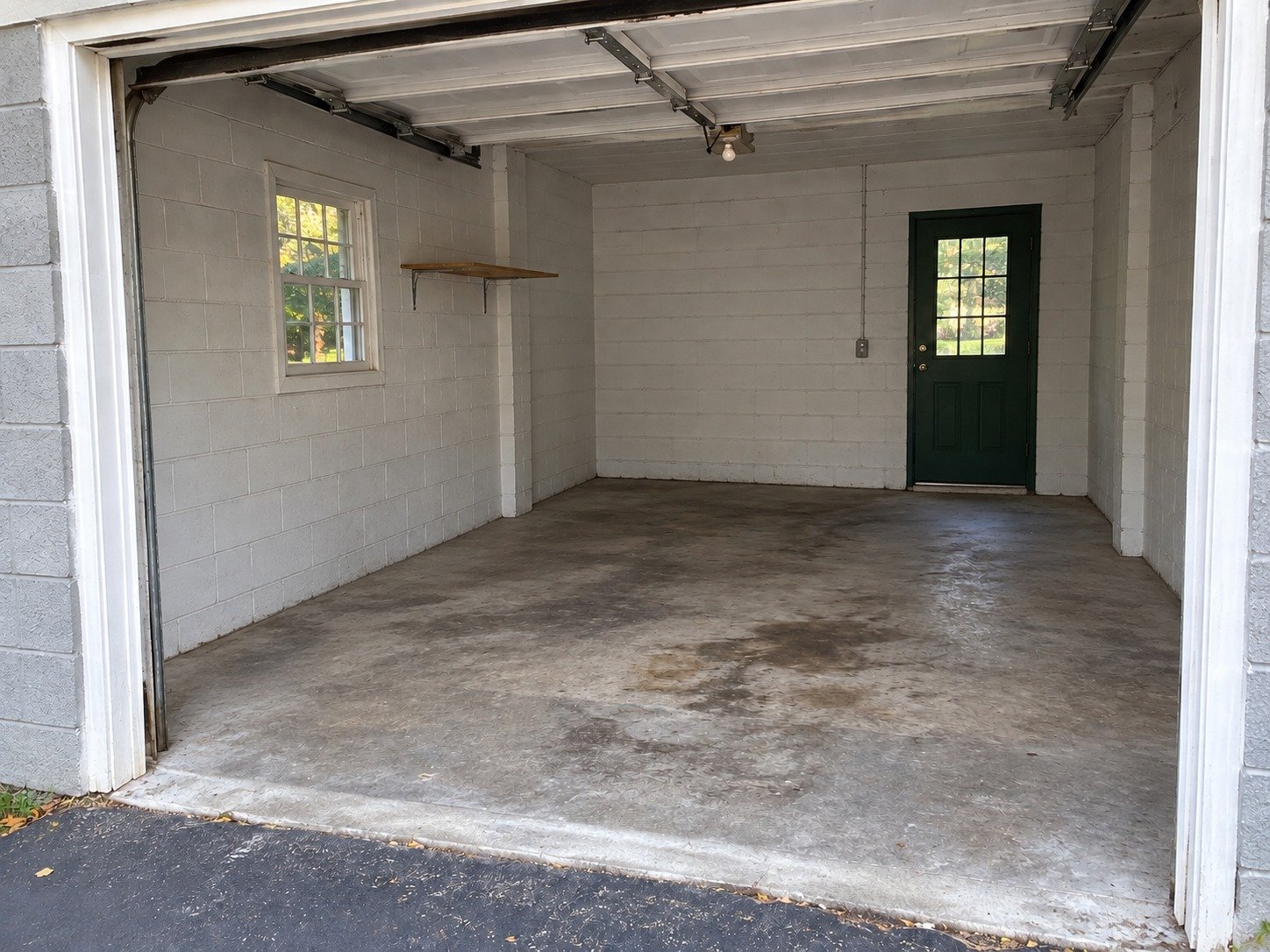 The same garage after contents-only cleanout, retaining the original worn floor and fixtures.