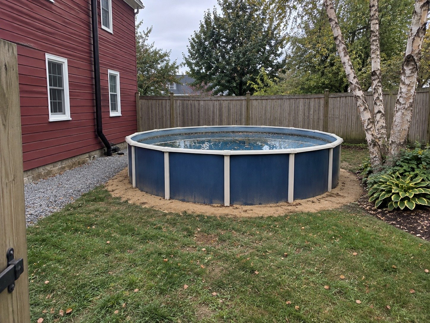 Existing above-ground pool in a fenced side yard before removal.