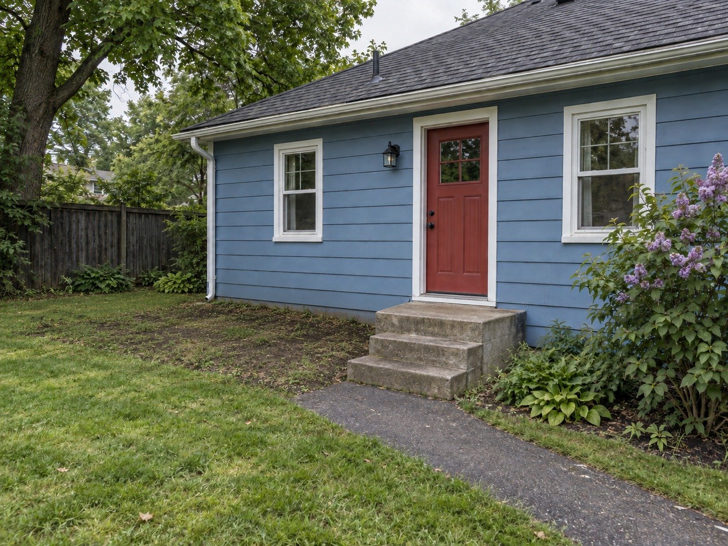 The same blue cottage after deck removal, with the original back-door steps and garden access retained.