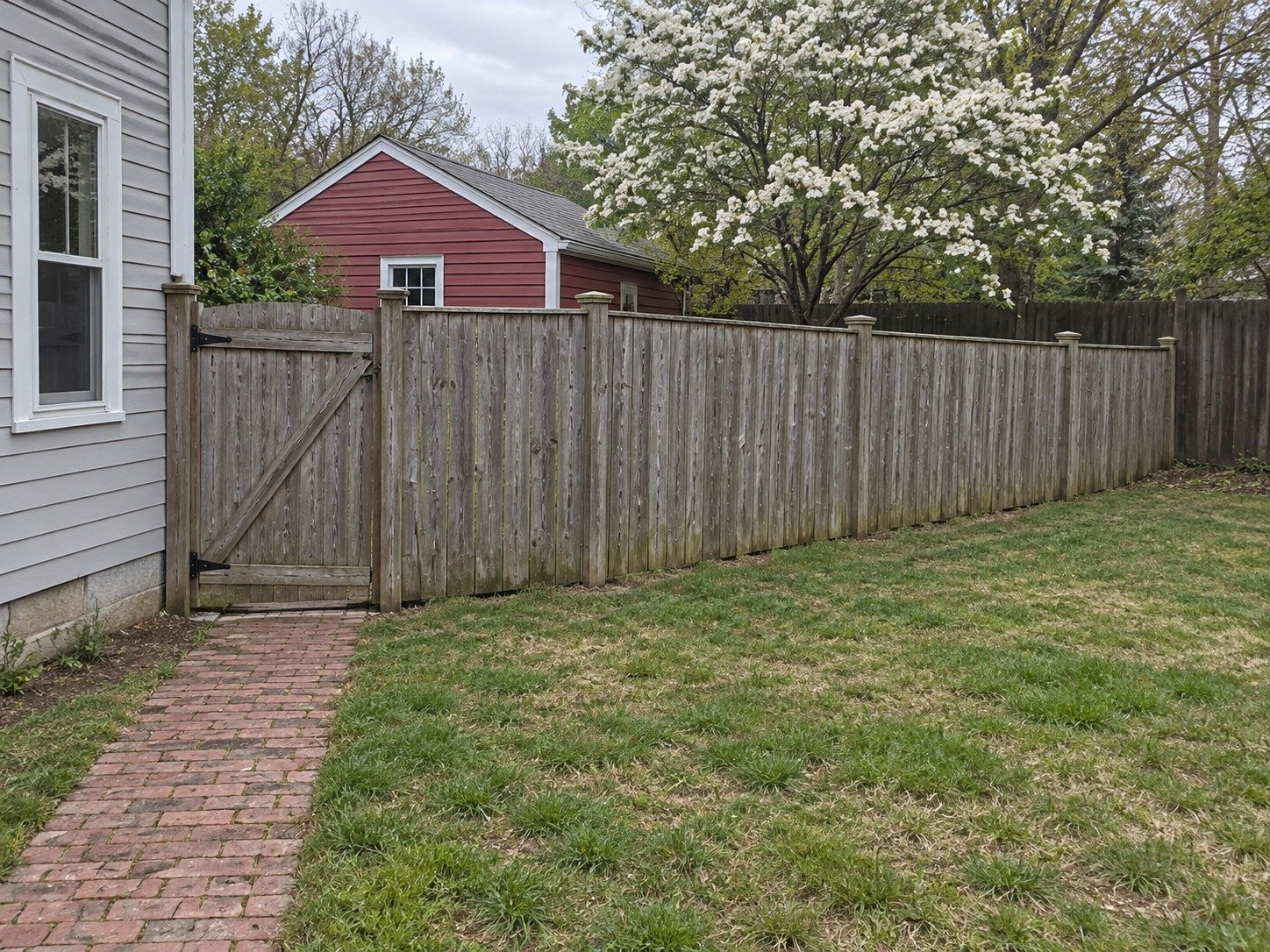 Weathered interior privacy fence and gate dividing a backyard before removal.