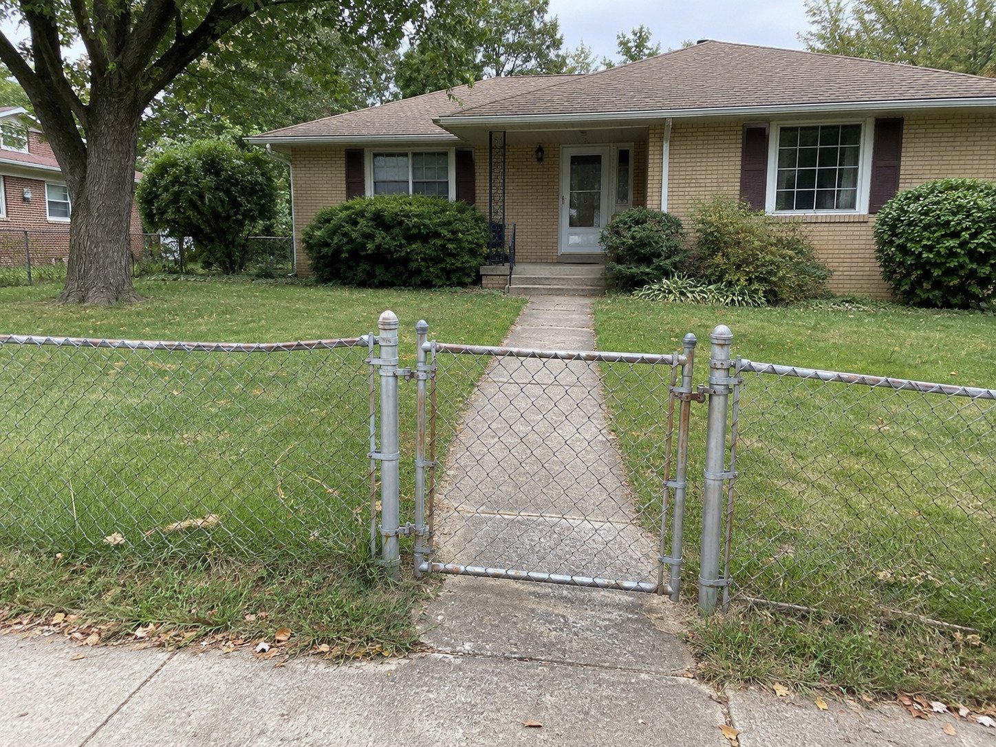 Worn chain-link fence and gate before replacement at a brick ranch.