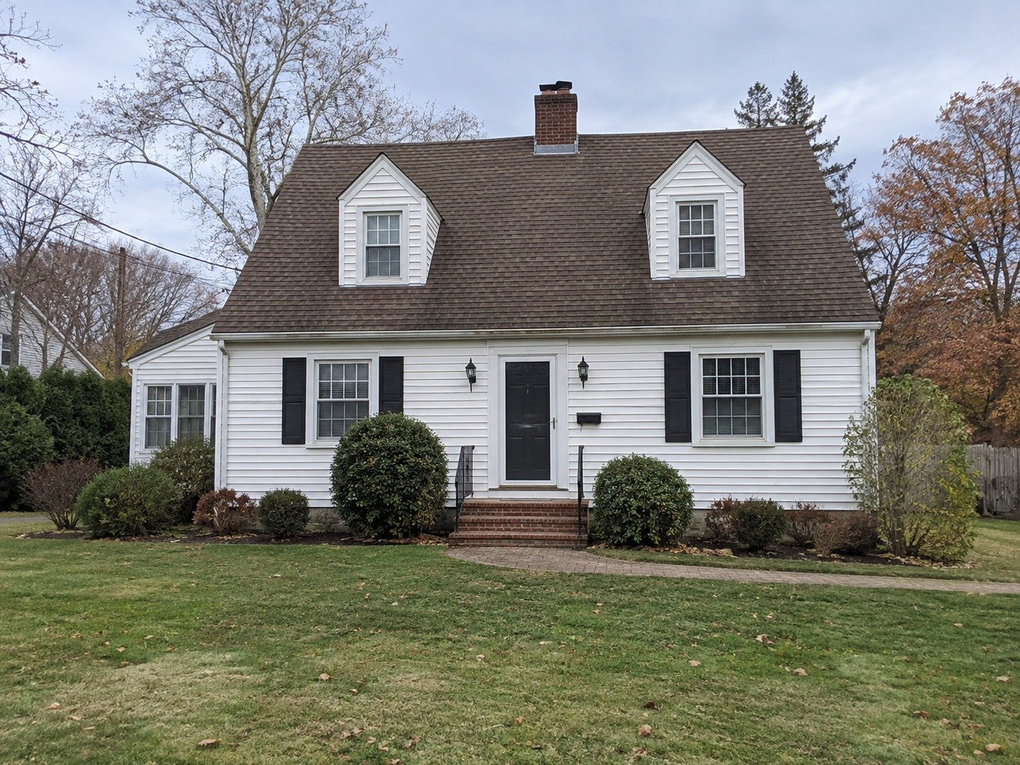 White Cape with a weathered brown shingle roof before replacement.