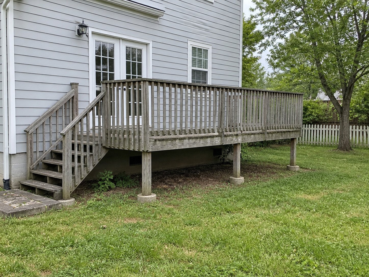Worn timber deck attached to French doors before replacement.