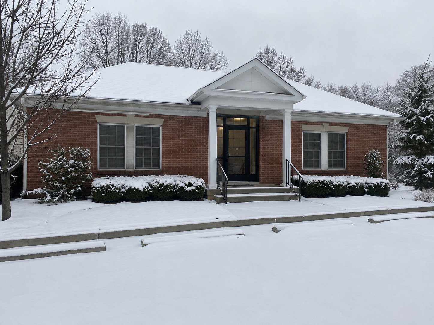 Snow-covered office parking court and entrance path before snow removal.