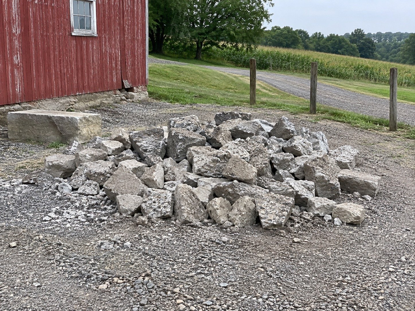 Concrete rubble stockpiled beside a rural outbuilding before processing.