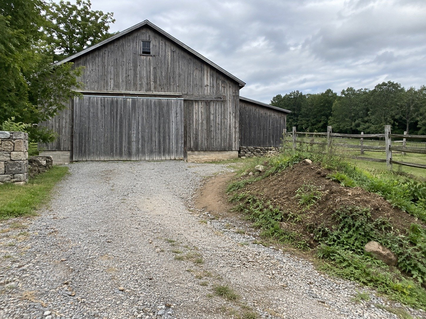 Uneven earth narrowing the turning area beside a barn before excavation.