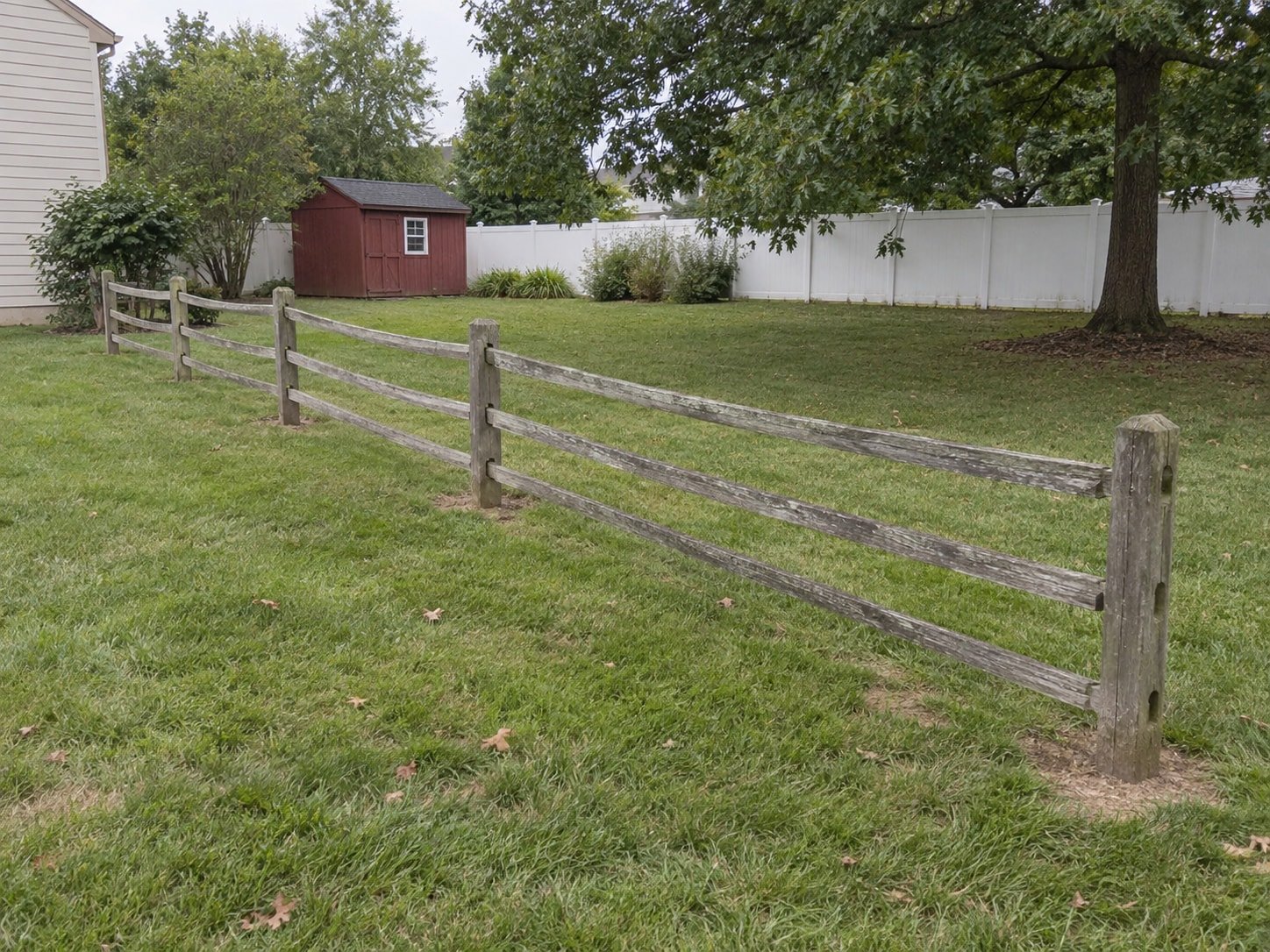 Old internal split-rail wood fence across a backyard before removal.