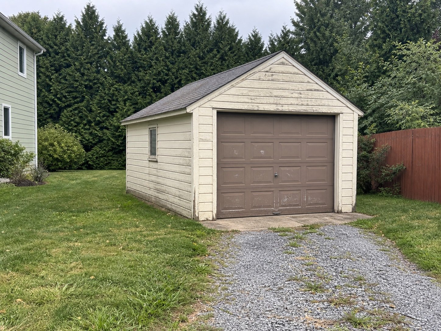 Aging detached garage beside a gravel driveway before teardown.