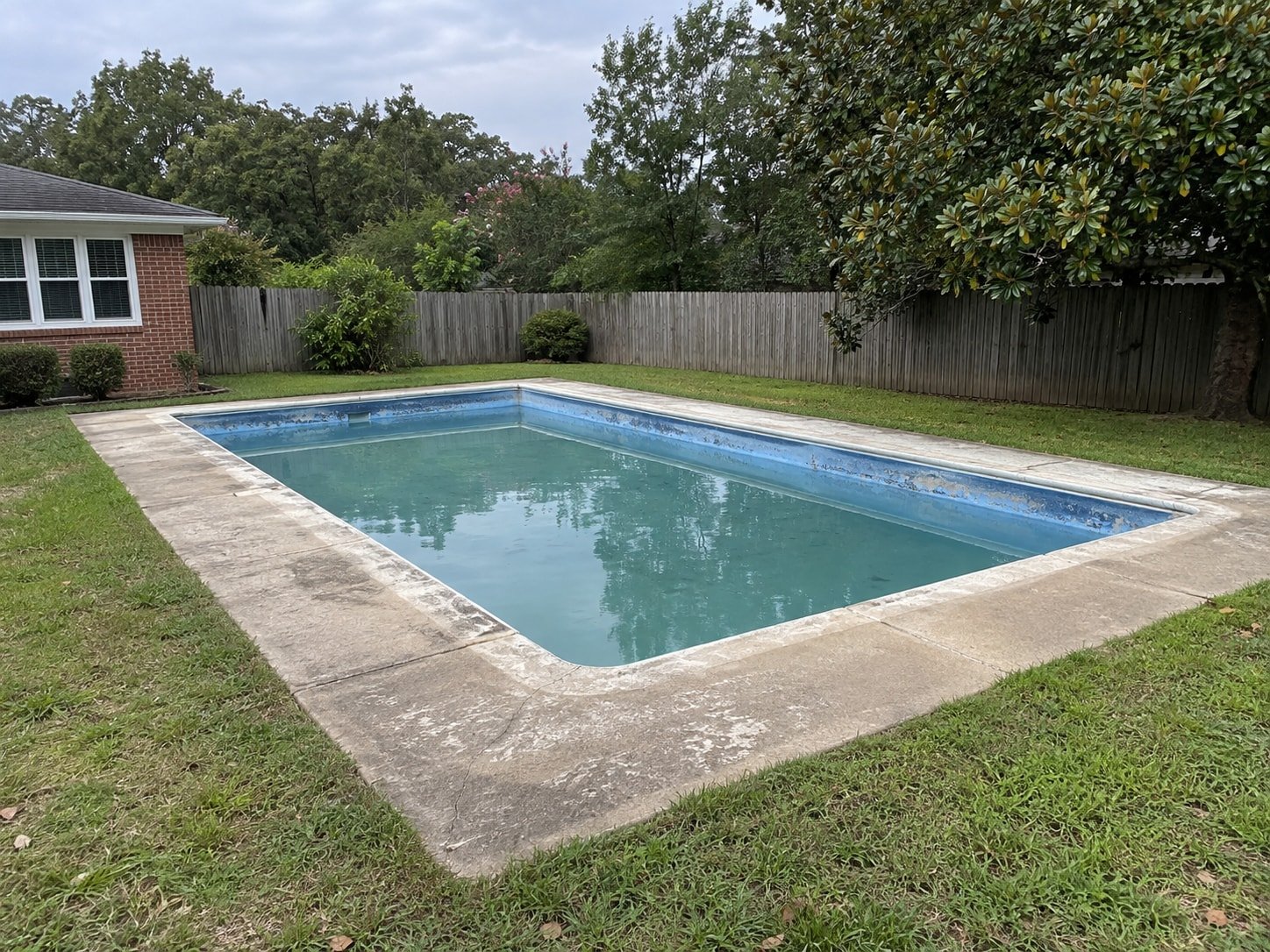 Aging backyard inground pool and concrete surround before removal.