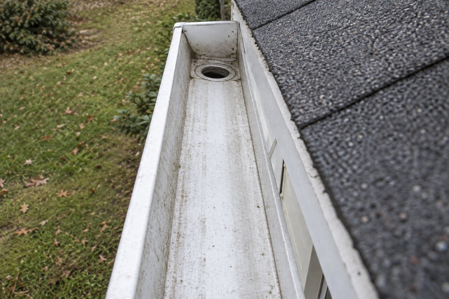 The same gutter and outlet from the same angle after cleaning, channel clear.