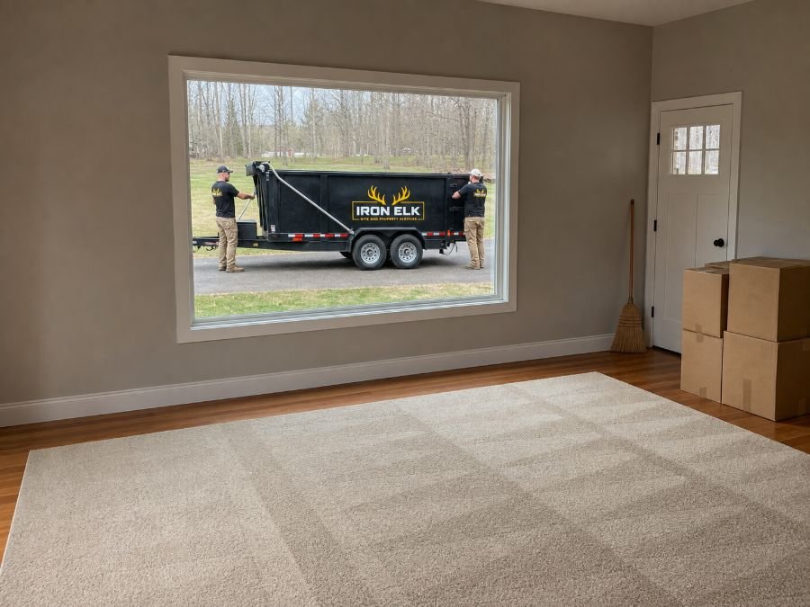 An emptied living room with a broom leaning by the door.