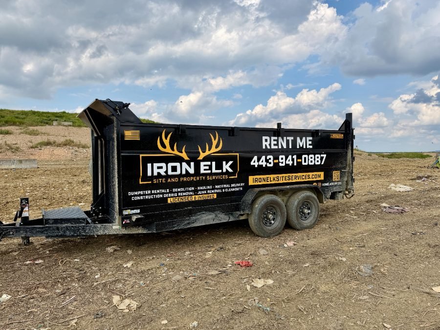 Black dumpster trailer on a level work site.