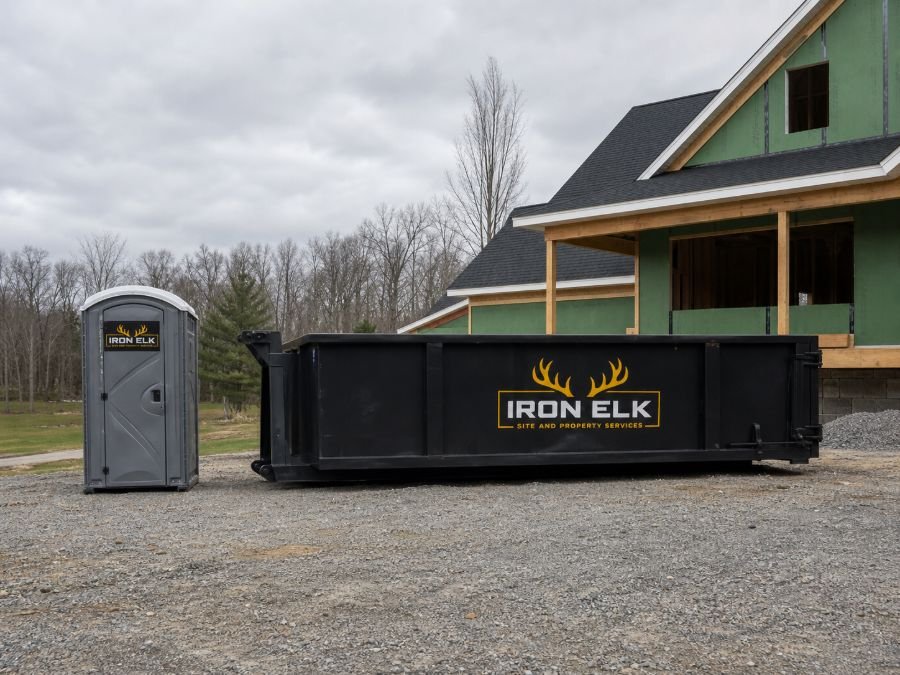 A clean portable toilet set beside a job-site container.