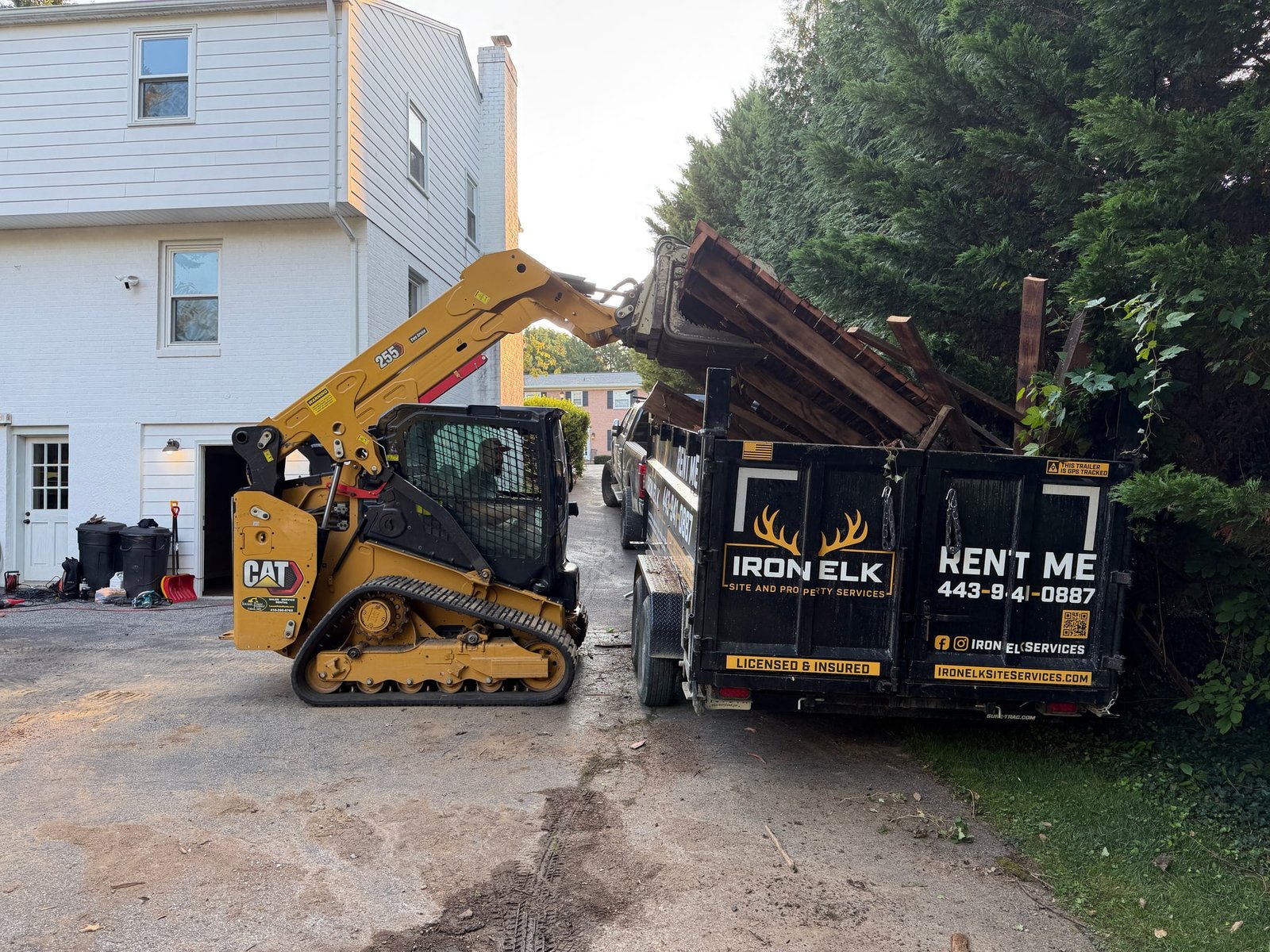 Iron Elk crew dismantling a wood deck, with the trailer positioned for loading the boards.