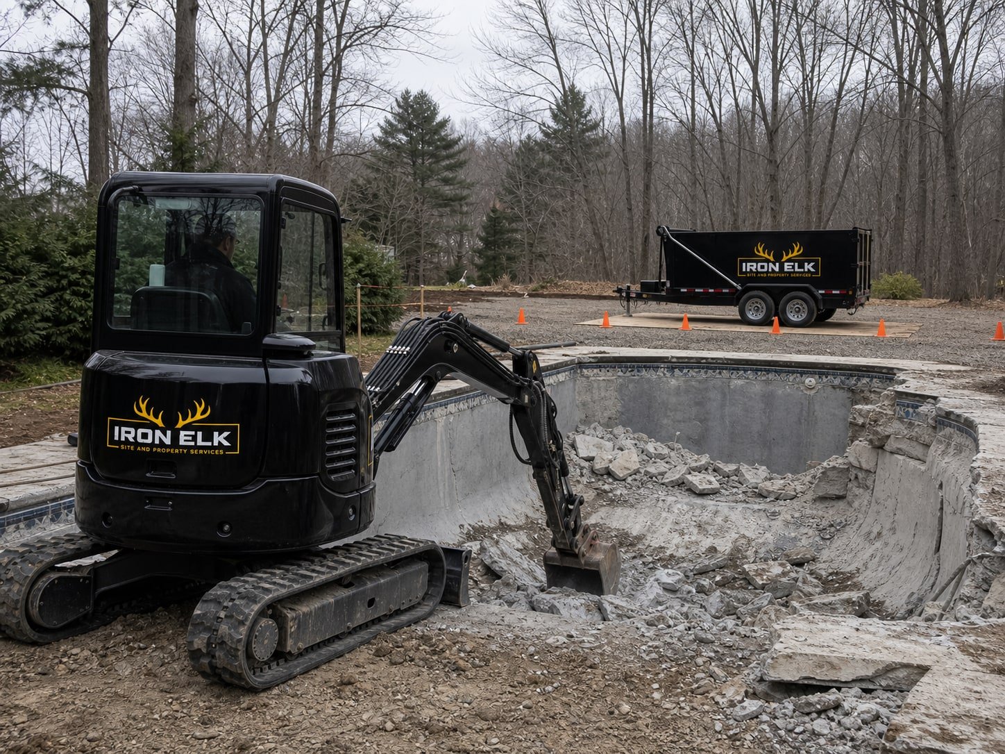 An excavator breaking up an inground pool shell.