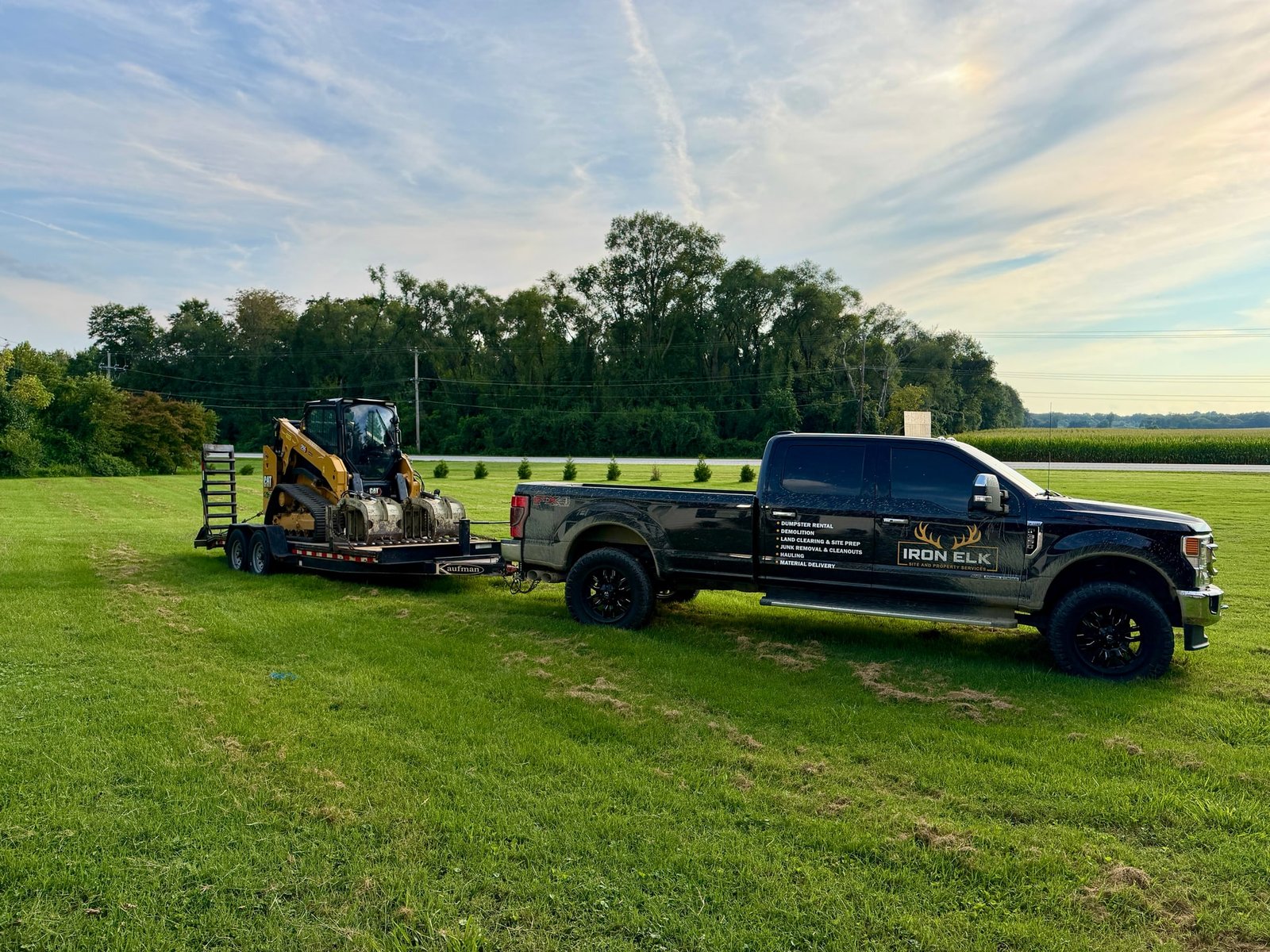 A skid steer chained down on the equipment trailer behind the dually.