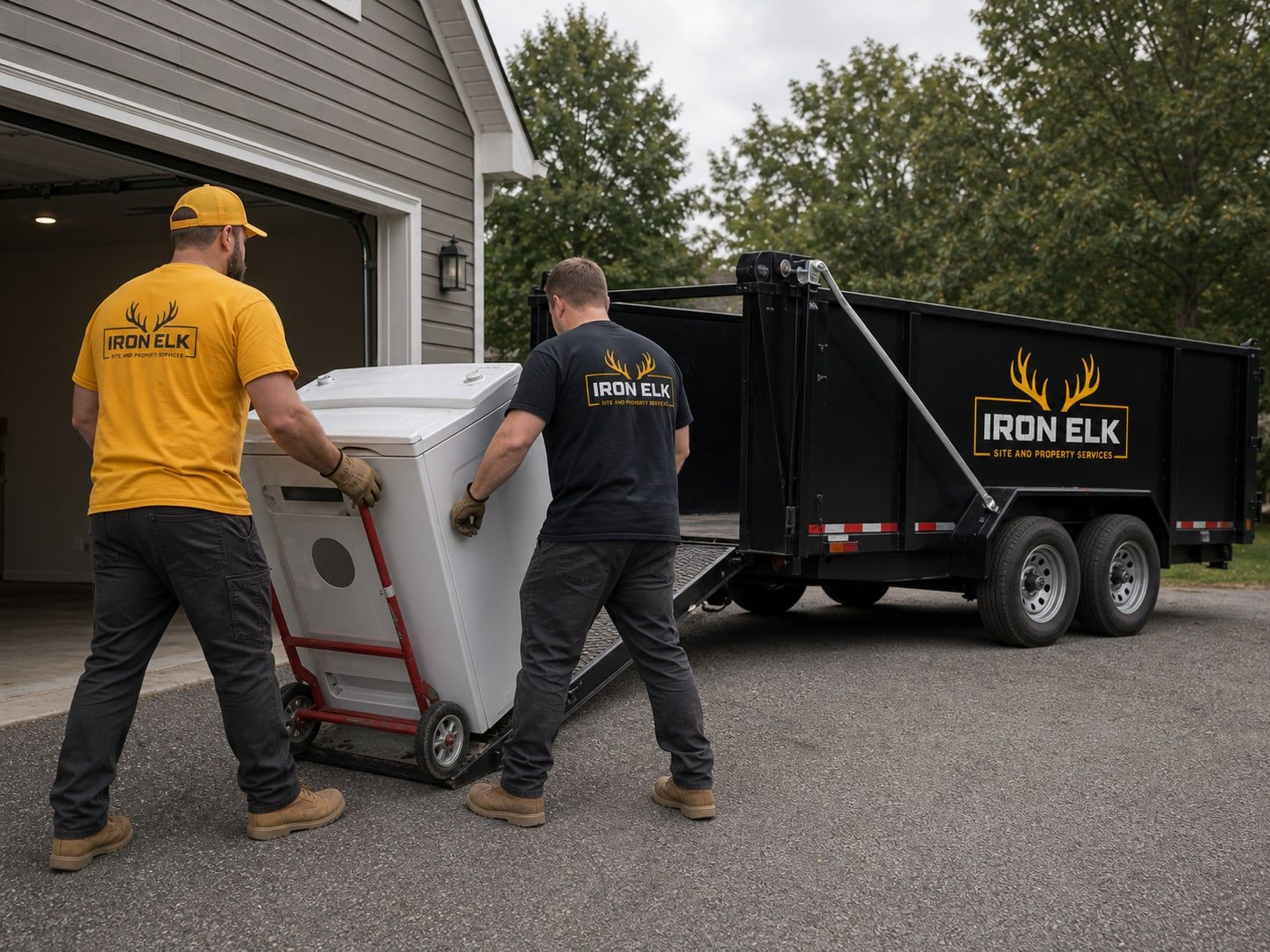 Two crew members wheeling a washer out on a dolly.