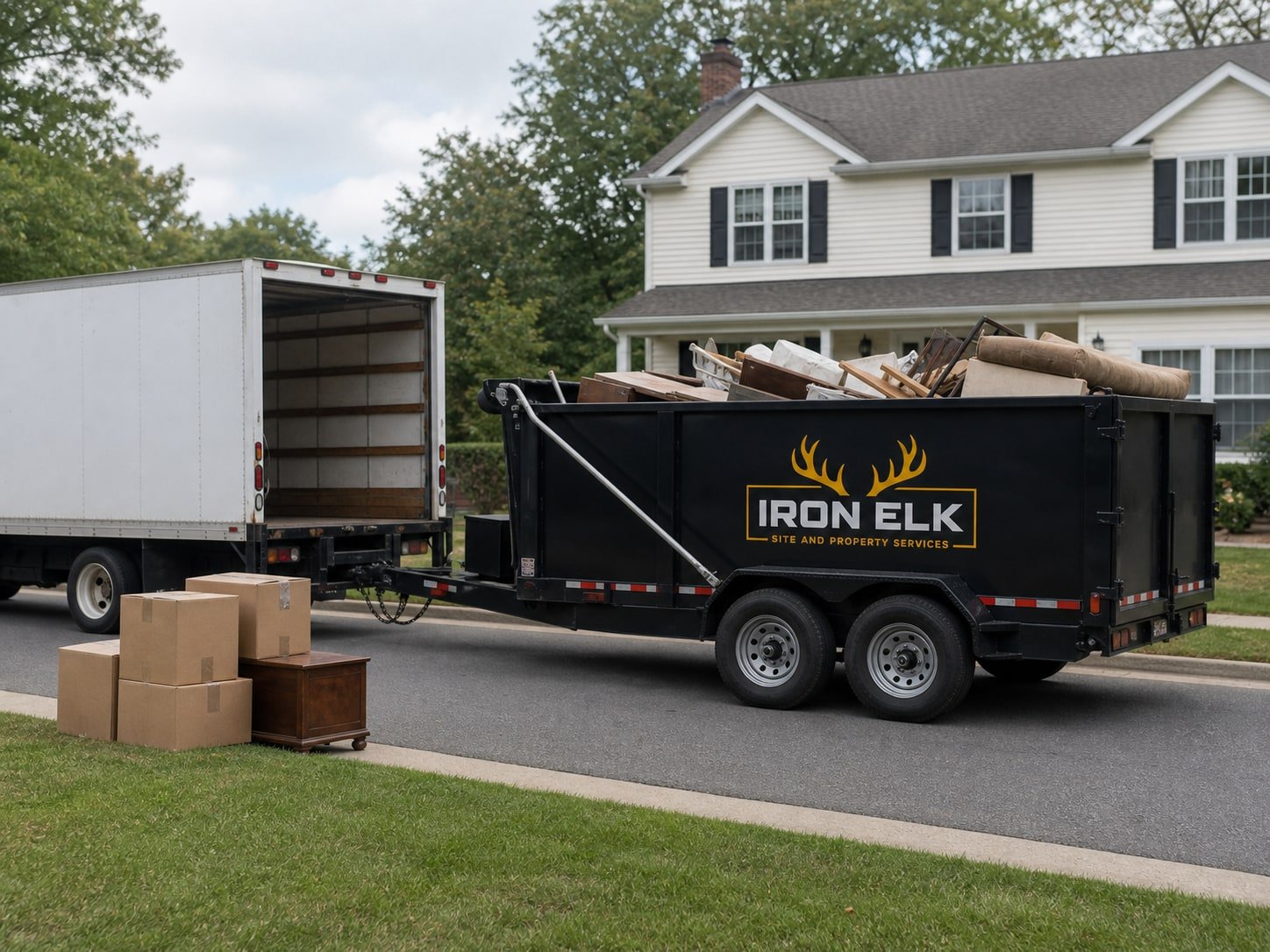 A loaded trailer in front of a house beside a moving truck.